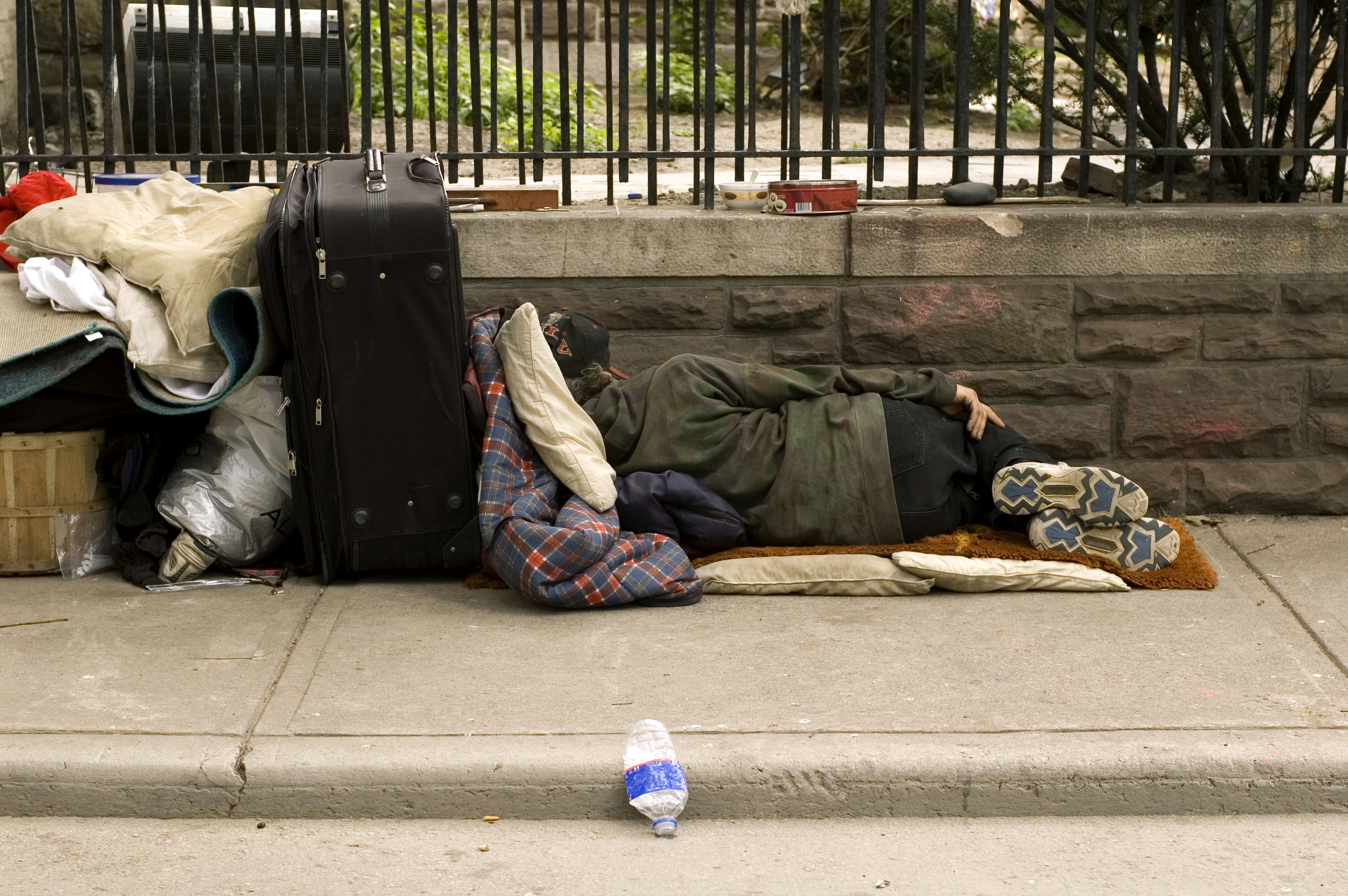 Street sleeping. Бездомный на улице с вещами.